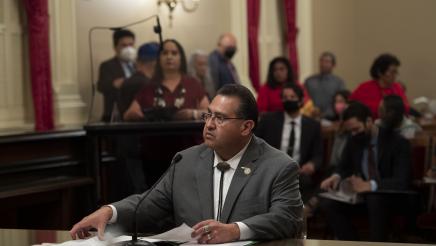Assemblymember James Ramos sitting behind a desk at a press conference for AB 1314