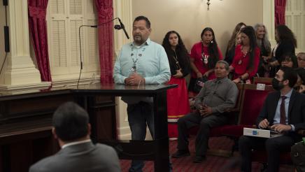 Man standing at a microphone speaking at a press conference for AB 1314