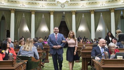 Assemblymember Ramos walking down the chamber floor with 2019 Woman of the Year Kristine Scott